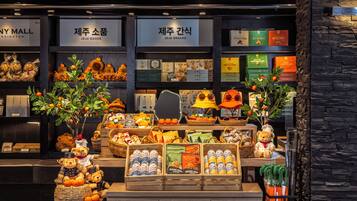 A display of various snacks and goods in a store with signs indicating 'JEJU GOODS' and 'JEJU SNACKS'.
