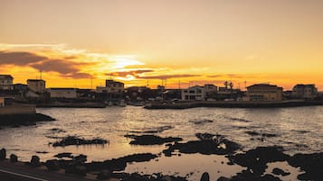 A coastal town at sunset with buildings along the water's edge.