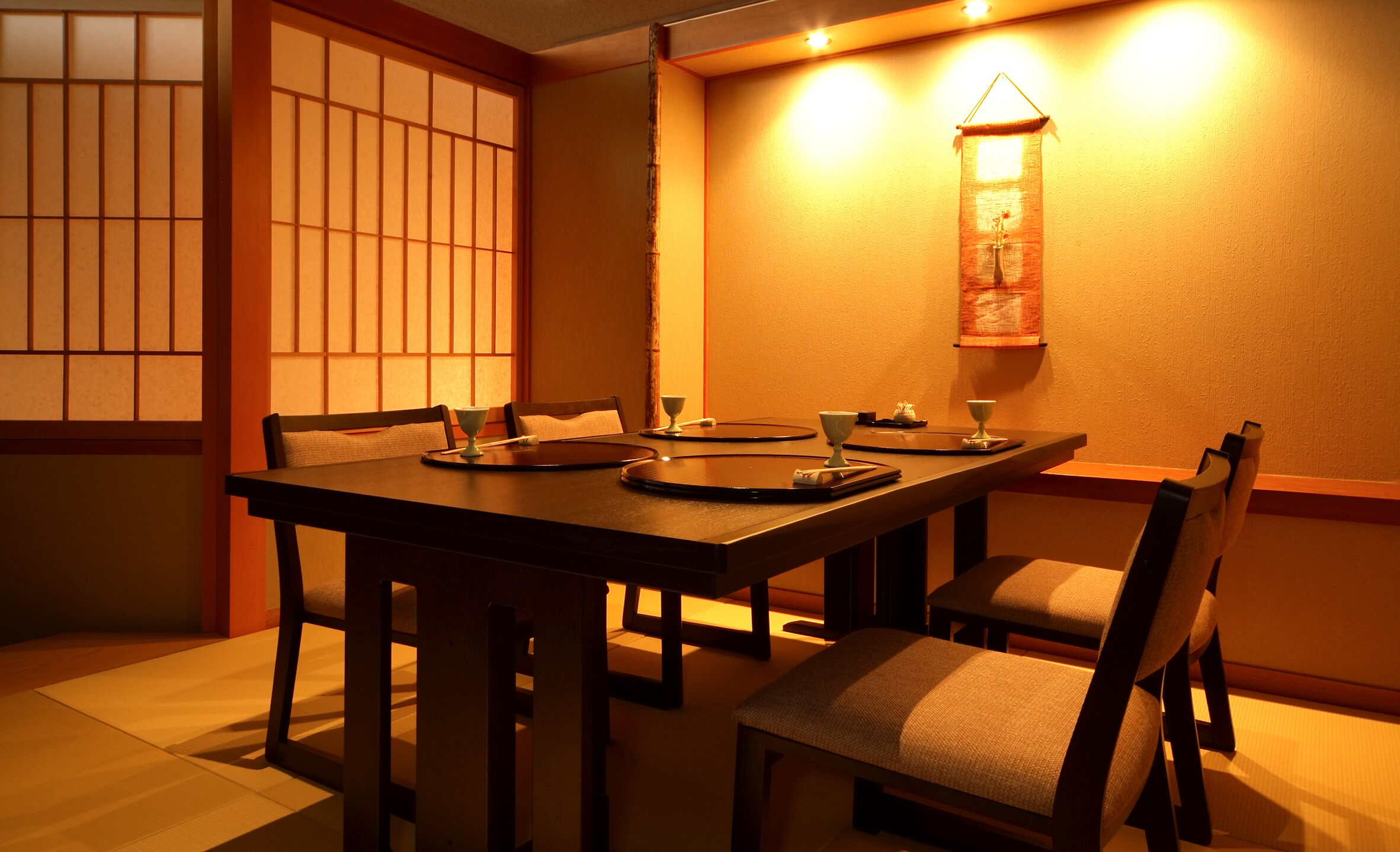 Une salle à manger de style japonais traditionnel, avec des tatamis, une table basse et des chaises en bois.