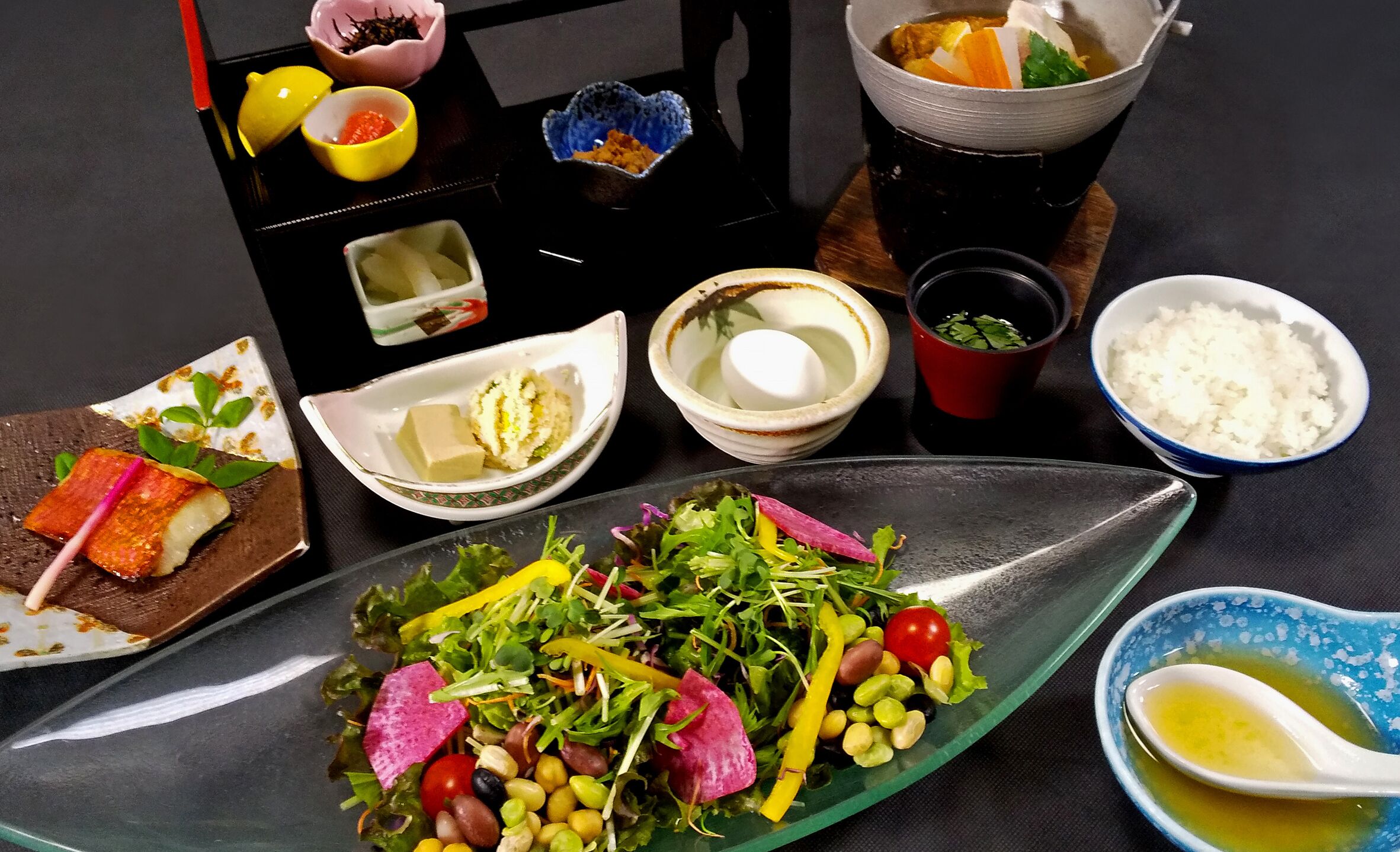 A variety of dishes including a salad, rice, and a bowl of soup.