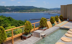 Une piscine sur le toit offrant une vue dégagée sur une ville côtière et les montagnes.