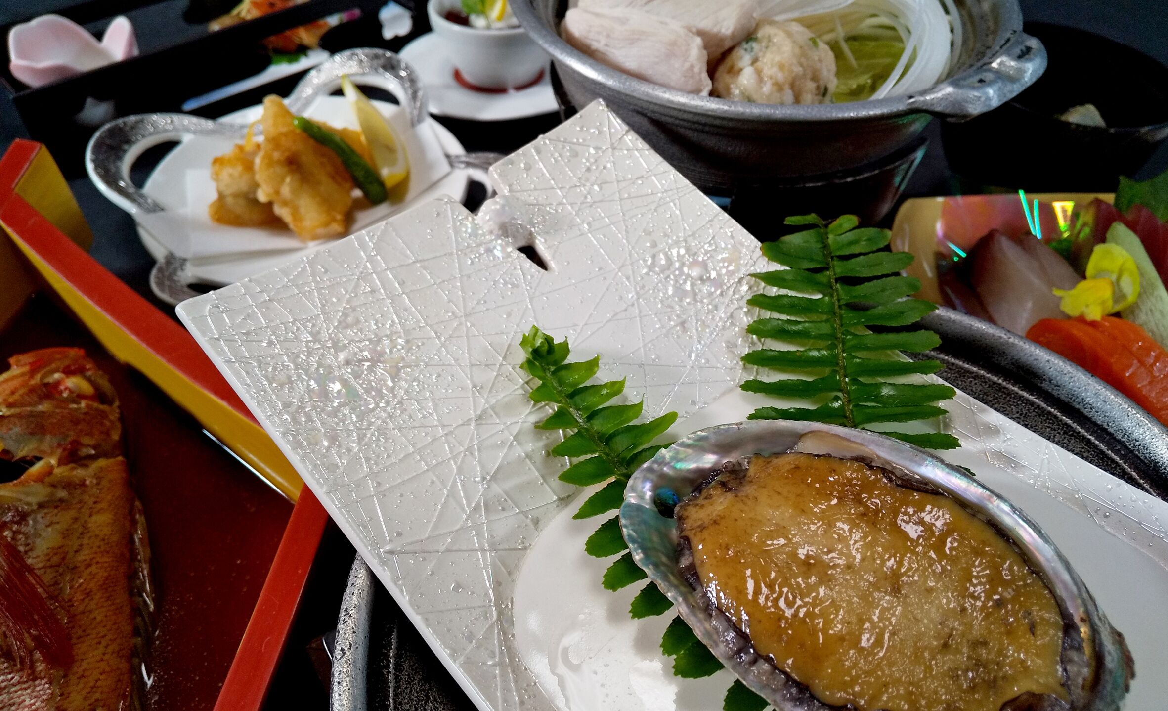 A tray with a variety of dishes including a piece of meat, a leafy garnish, and a baked item.