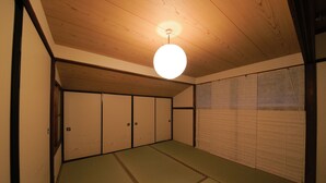 Una habitación con suelo de tatami, vigas de madera en el techo y puertas correderas.