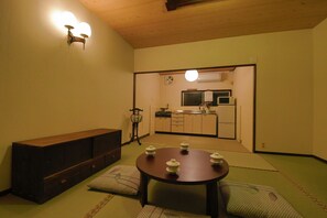 A traditional Japanese room with tatami flooring, a low wooden table with tea sets, a wooden bench, and a kitchen visible through an open doorway. - Kyomachiya Higashihonganji-an (Kyoto)