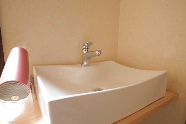 A bathroom with a white sink, a chrome faucet, and a pink hairdryer on a wooden shelf. - Kyomachiya Higashihonganji-an (Kyoto)