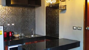 Una cocina moderna con encimera negra, pileta de acero inoxidable y microondas.