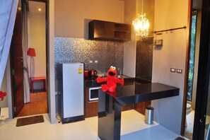 Una cocina moderna con encimera negra, un peluche rojo y una araña.