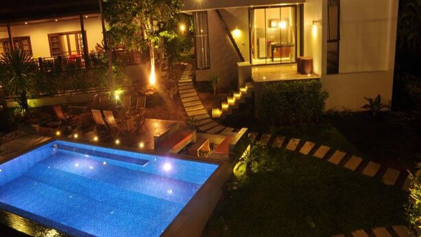 Una casa moderna con piscina, mobiliario exterior y una escalera que lleva a una terraza.