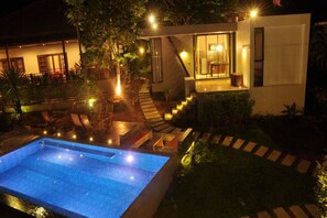 Una casa moderna con piscina, mobiliario exterior y una escalera que lleva a una terraza.