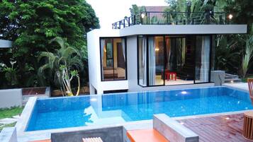 Una piscina al aire libre, sillones reclinables de piscina