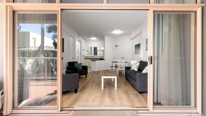 A modern interior with a sliding glass door leading to a living area, a kitchen, and a dining space. - Charlesworth Bay Beach Resort (Coffs Harbour)