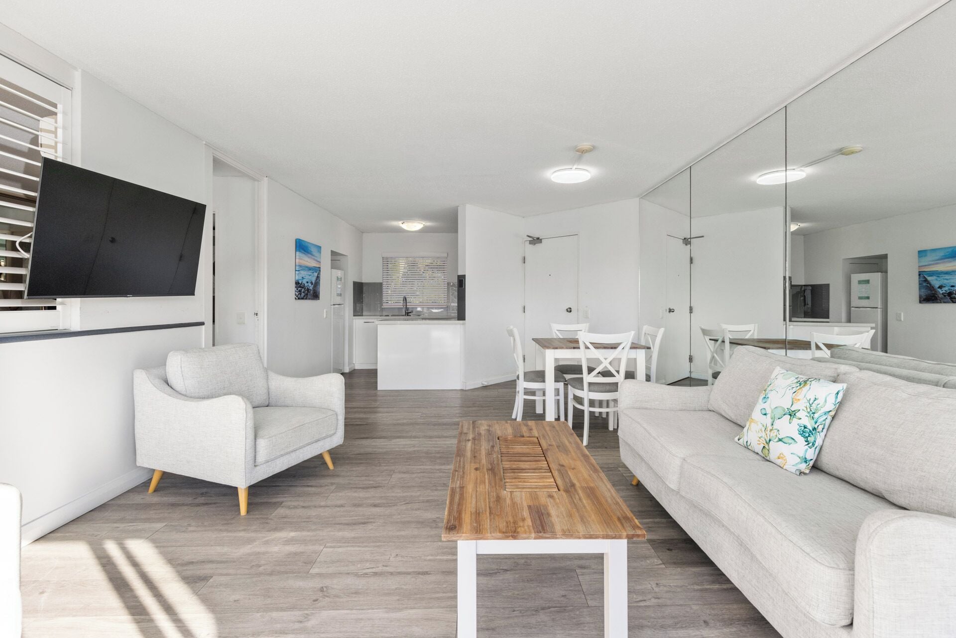 Una sala moderna con un sofá, una mesa de centro y un televisor montado en la pared.