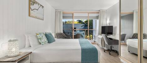 Habitación de hotel moderna con una cama grande, un escritorio con computadora y una zona de estar con sillas.