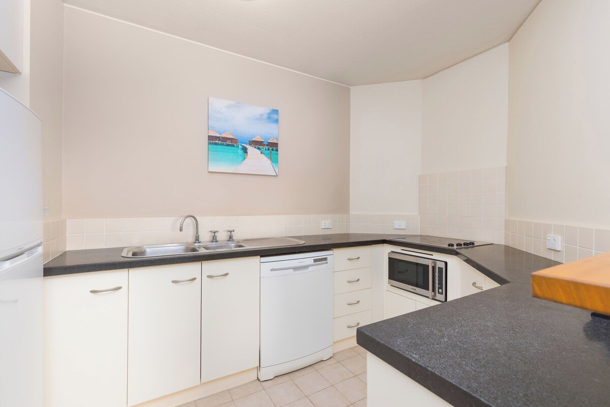 A kitchen with white cabinets, a dishwasher, a stove, and a microwave.