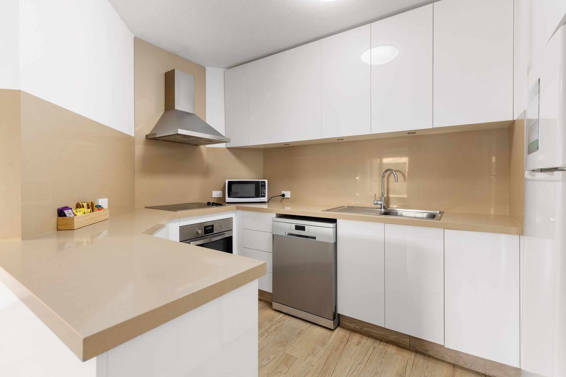 A modern kitchen with white cabinets, stainless steel appliances, a microwave, a dishwasher, and a sink.