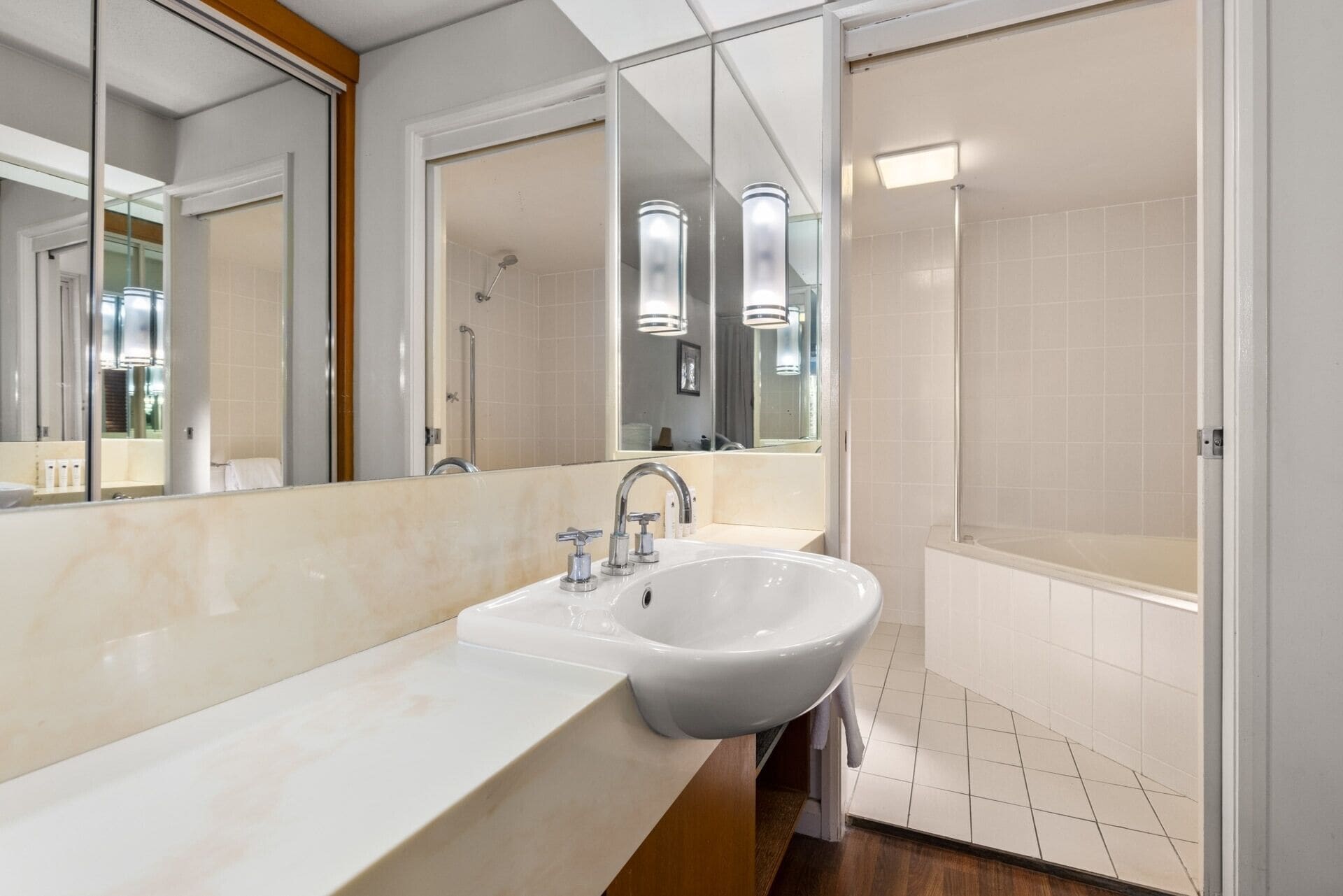 A modern bathroom with a large sink, a mirror, and a shower area.