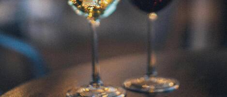 Dos copas de vino sobre una mesa de madera con luces desenfocadas al fondo.