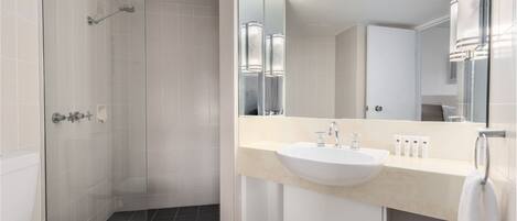 Un baño moderno con cabina de ducha, inodoro y lavabo con un espejo grande.