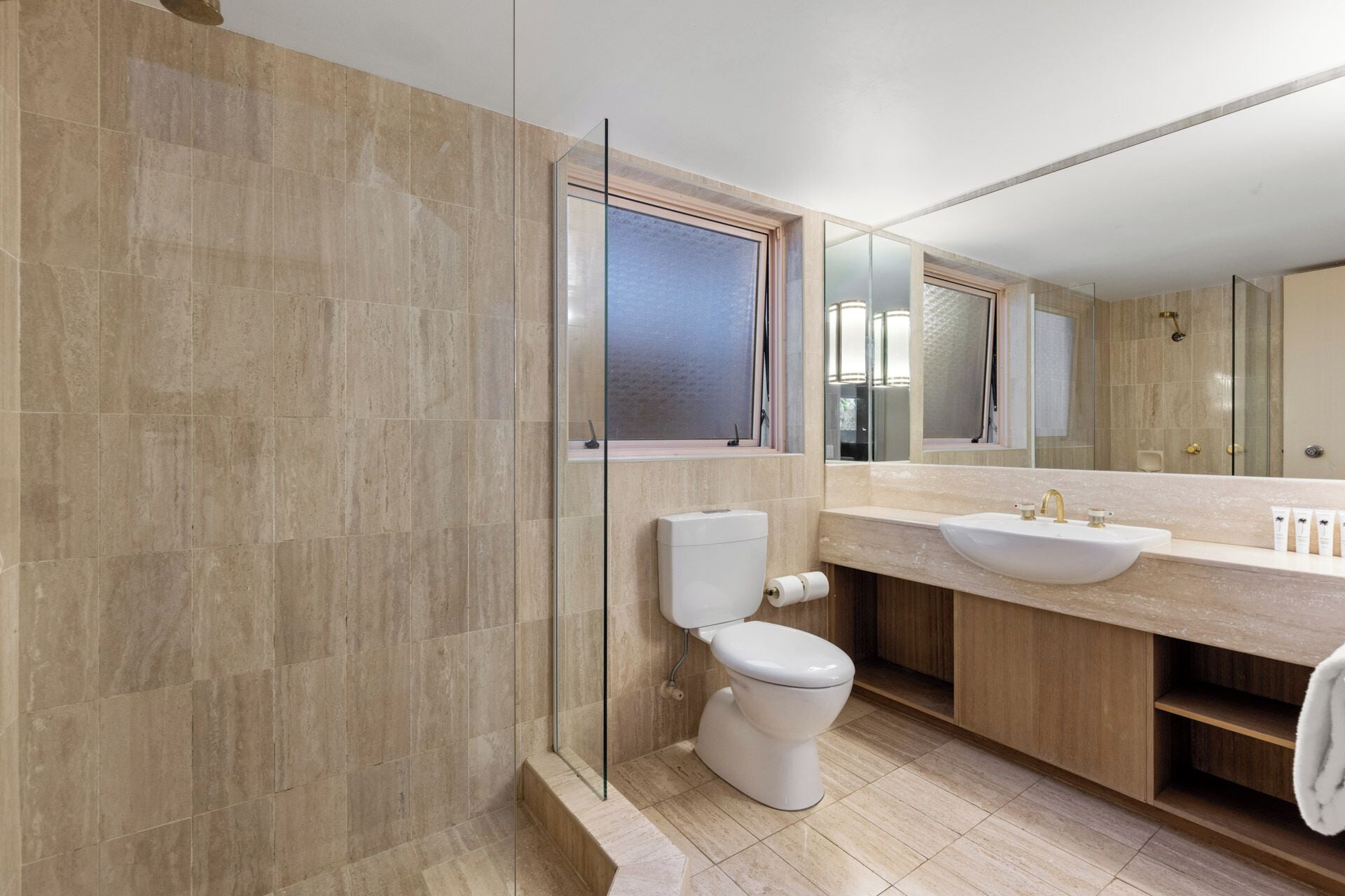 A modern bathroom with a glass shower enclosure, a toilet, and a vanity with a sink and mirror.