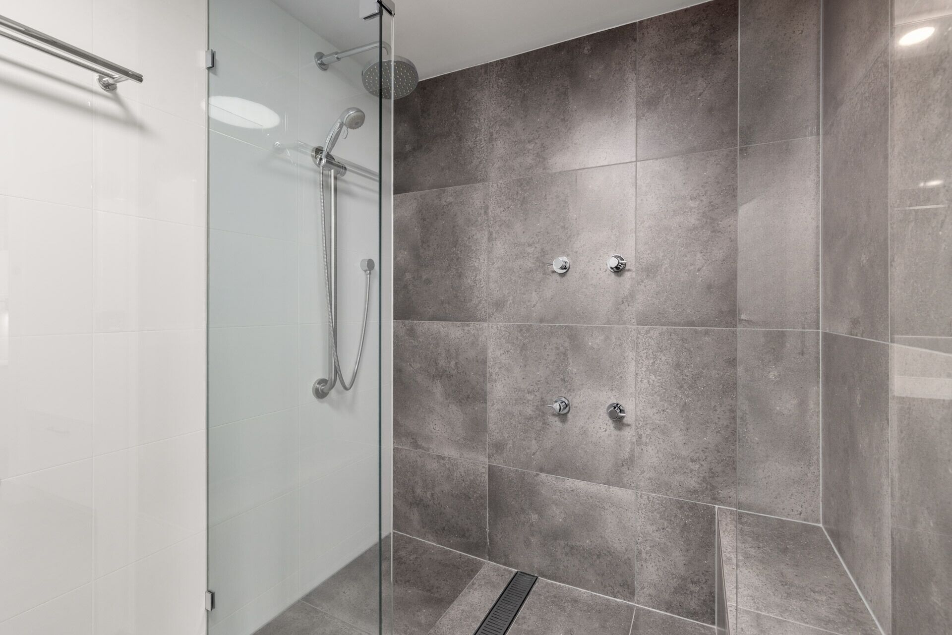 Ein modernes Duschbad mit Glastür, Handbrause und Wandarmatur.