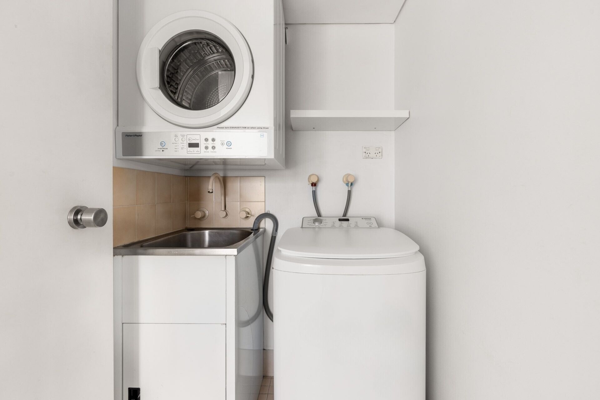A compact laundry area with a front-loading washing machine, a built-in dryer, and a sink.
