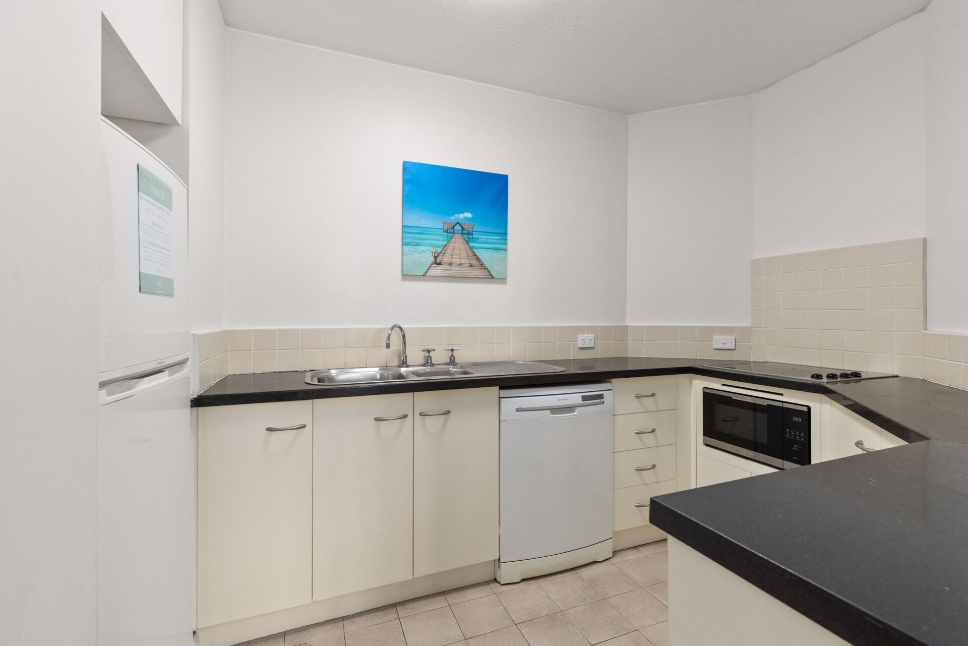 A compact kitchen with a dishwasher, a microwave, and a sink.