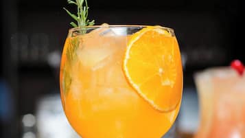 Un verre à cocktail garni d’une tranche d’orange et d’une branche de romarin.