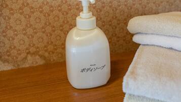 A bottle of lotion and a stack of towels on a wooden surface.