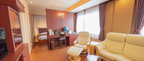 Habitación de hotel con cama, escritorio con globo terráqueo, sillón de cuero, sofá y televisión.