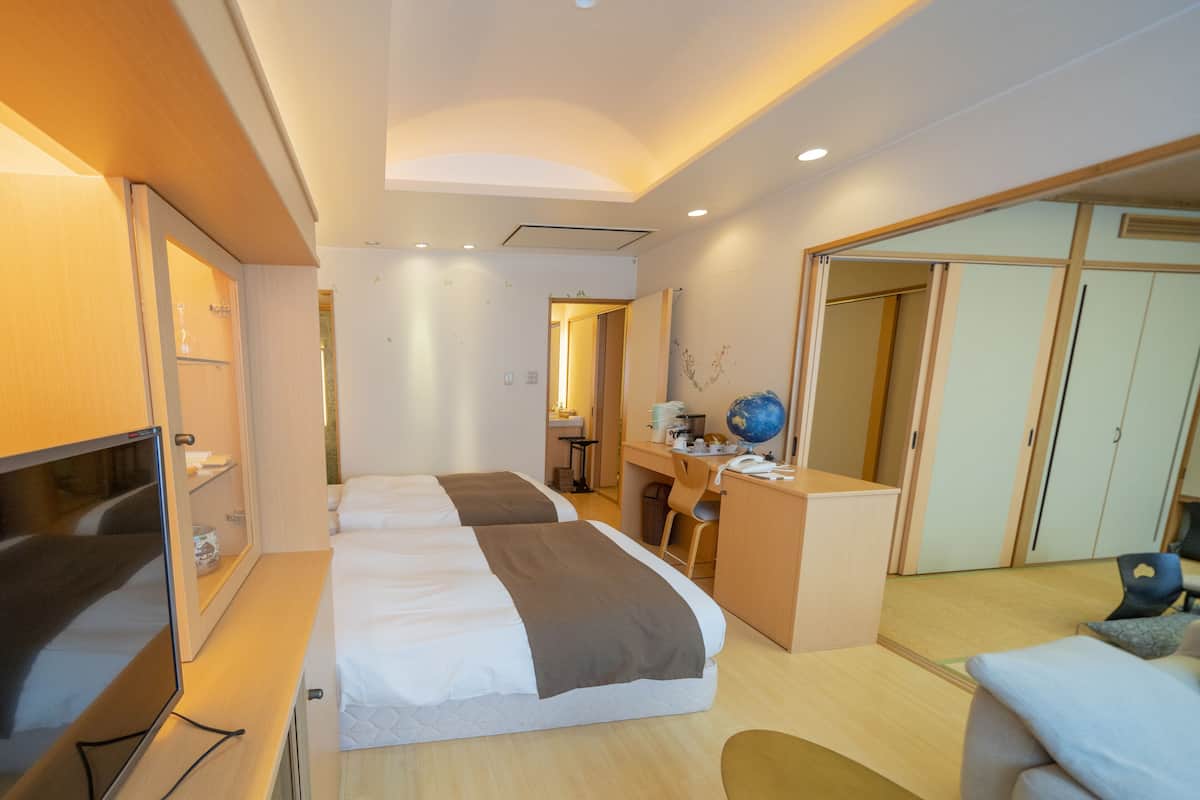 A hotel room with a bed, desk, and wardrobe.