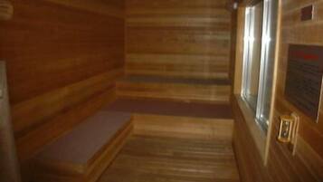 Interior de uma cabana de madeira com um banco, uma janela e uma placa na parede.