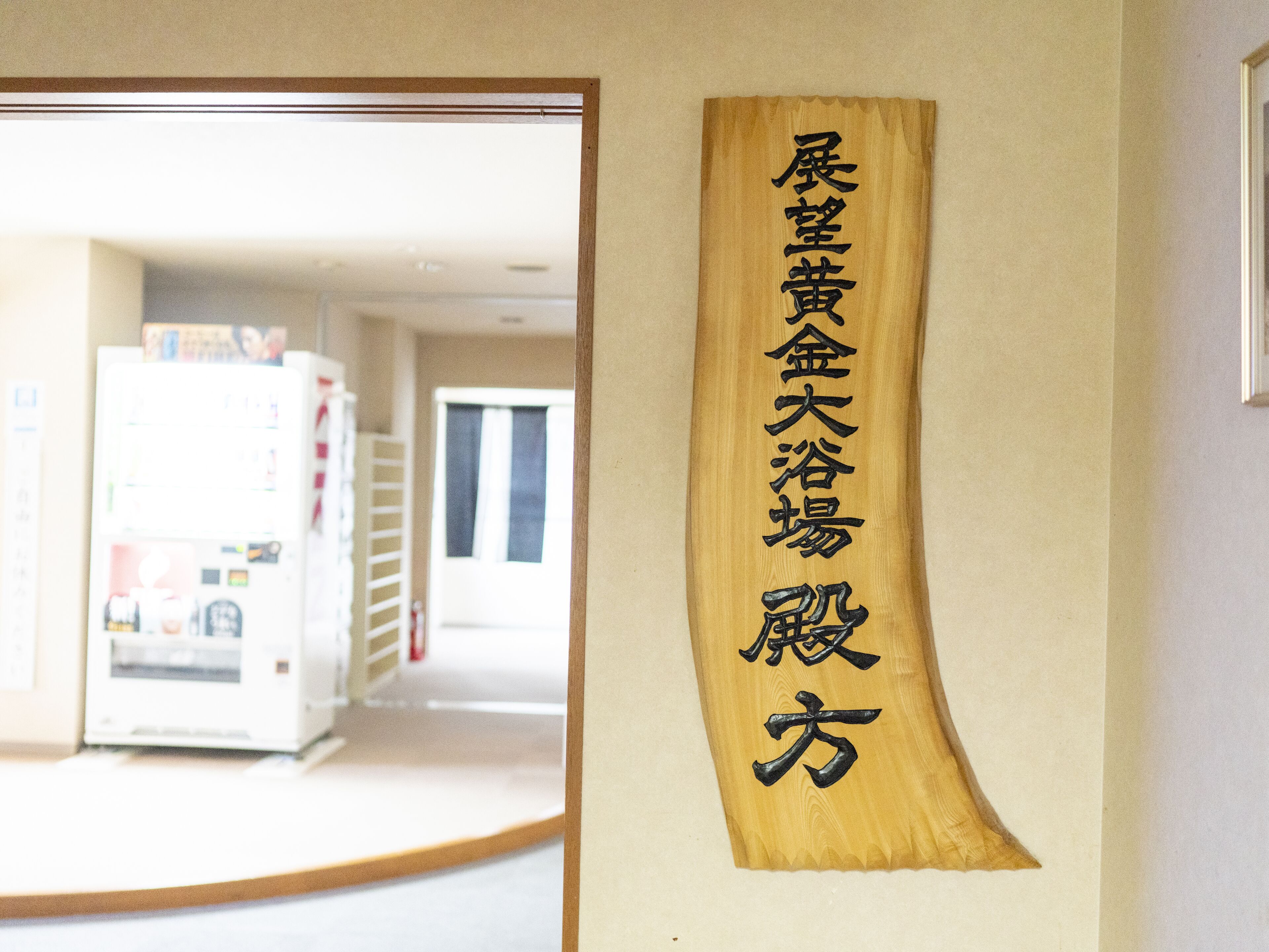 A wooden sign with Japanese characters on a wall.