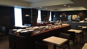 Ein reichhaltiges Buffet mit mehreren Servierstationen, Tischen und Stühlen in einem großzügigen Raum.