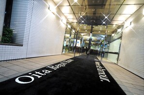 Un couloir recouvert d’un tapis noir qui mène à une porte d’entrée en verre.