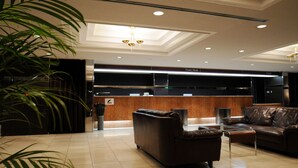 Eine moderne Lobby mit einer Rezeption, Ledersitzgelegenheiten und einer großen Pflanze.