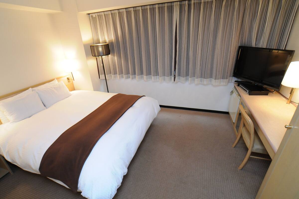 Une chambre d’hôtel équipée d’un lit, d’une télévision, d’un bureau et d’une lampe.