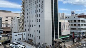 Ein mehrstöckiges Hotel mit modernem Design, das durch einen markanten, vertikalen Gebäudeteil mit großen Fenstern und eine Beschilderung in einer Fremdsprache gekennzeichnet ist.