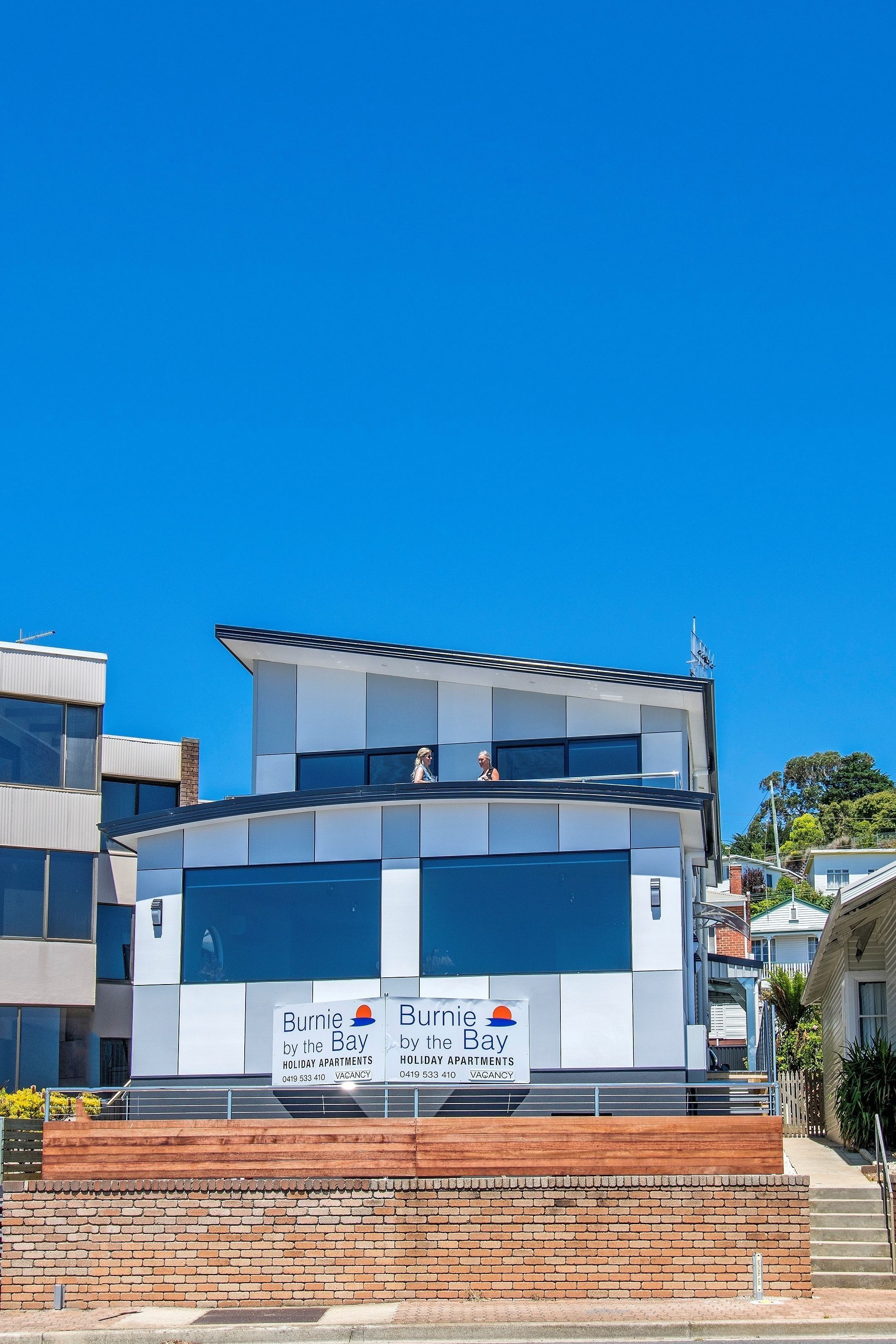 A modern building with a sign advertising "Burnie by the Bay Holiday Apartments."