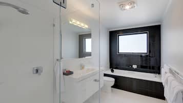 A modern bathroom with a glass shower enclosure, a white sink, a black bathtub, and a large mirror.
