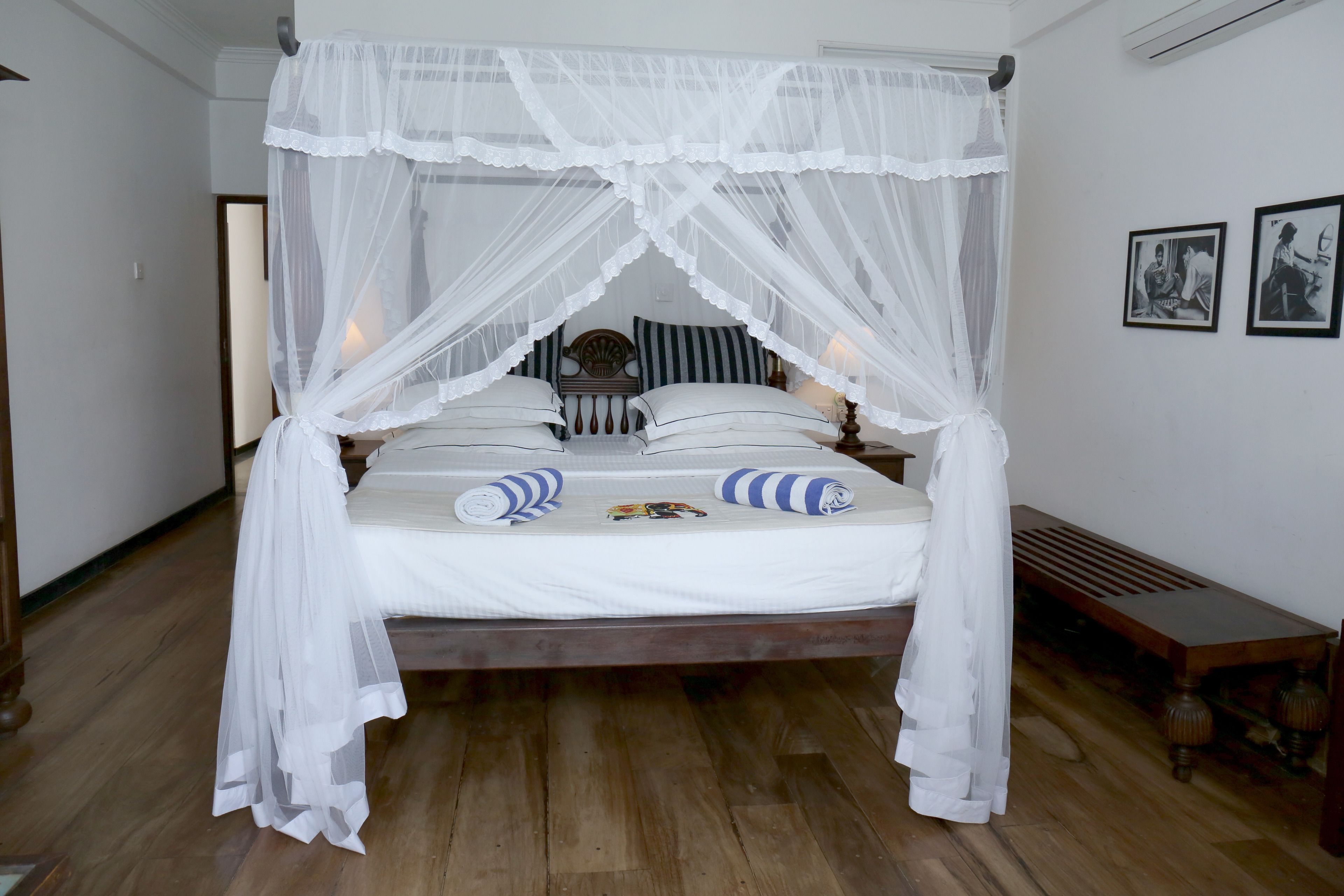 A bed with a canopy, striped pillows, and a bedside table.