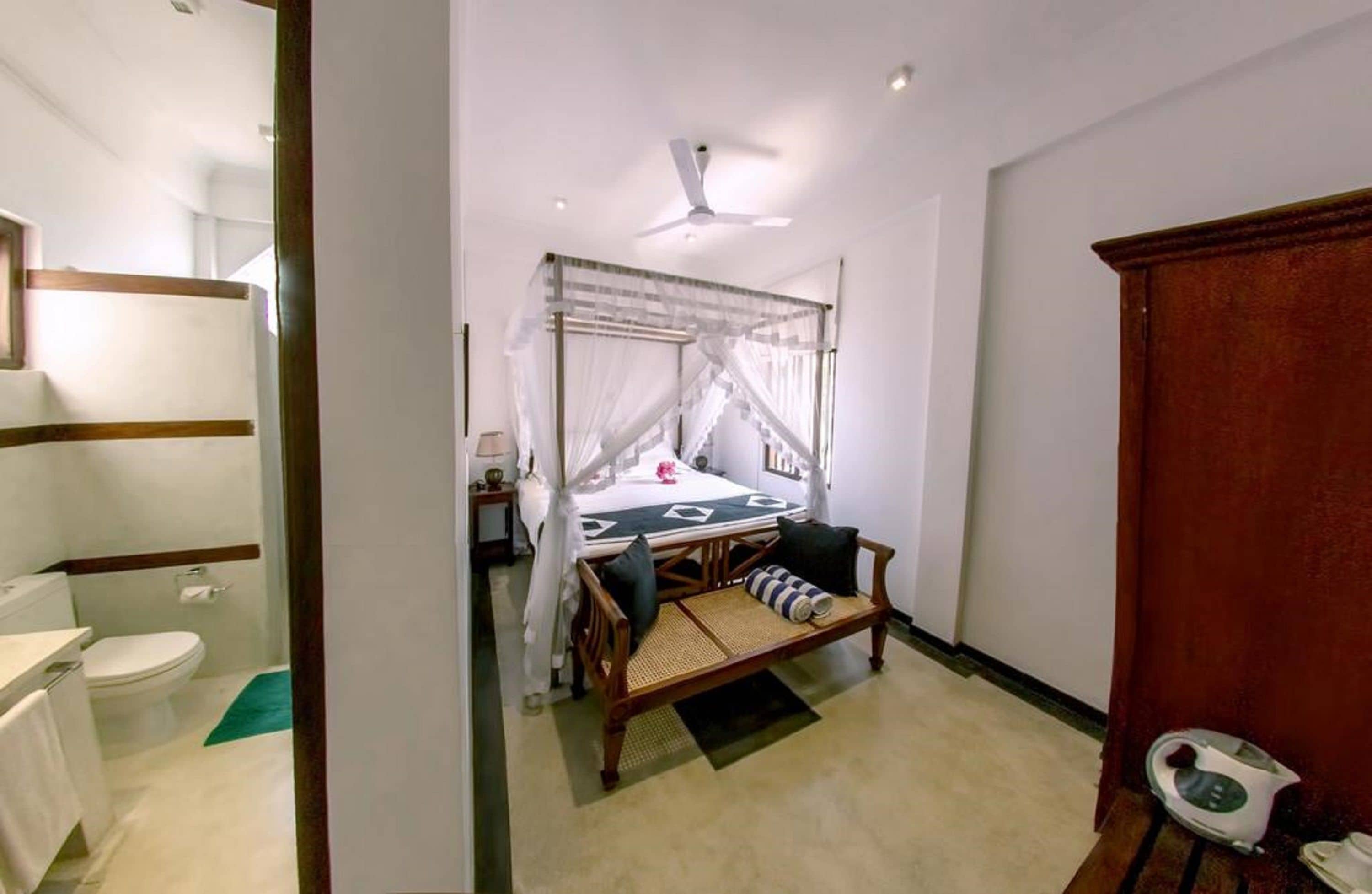 Un dormitorio con cama, mesita de noche y ventilador de techo.