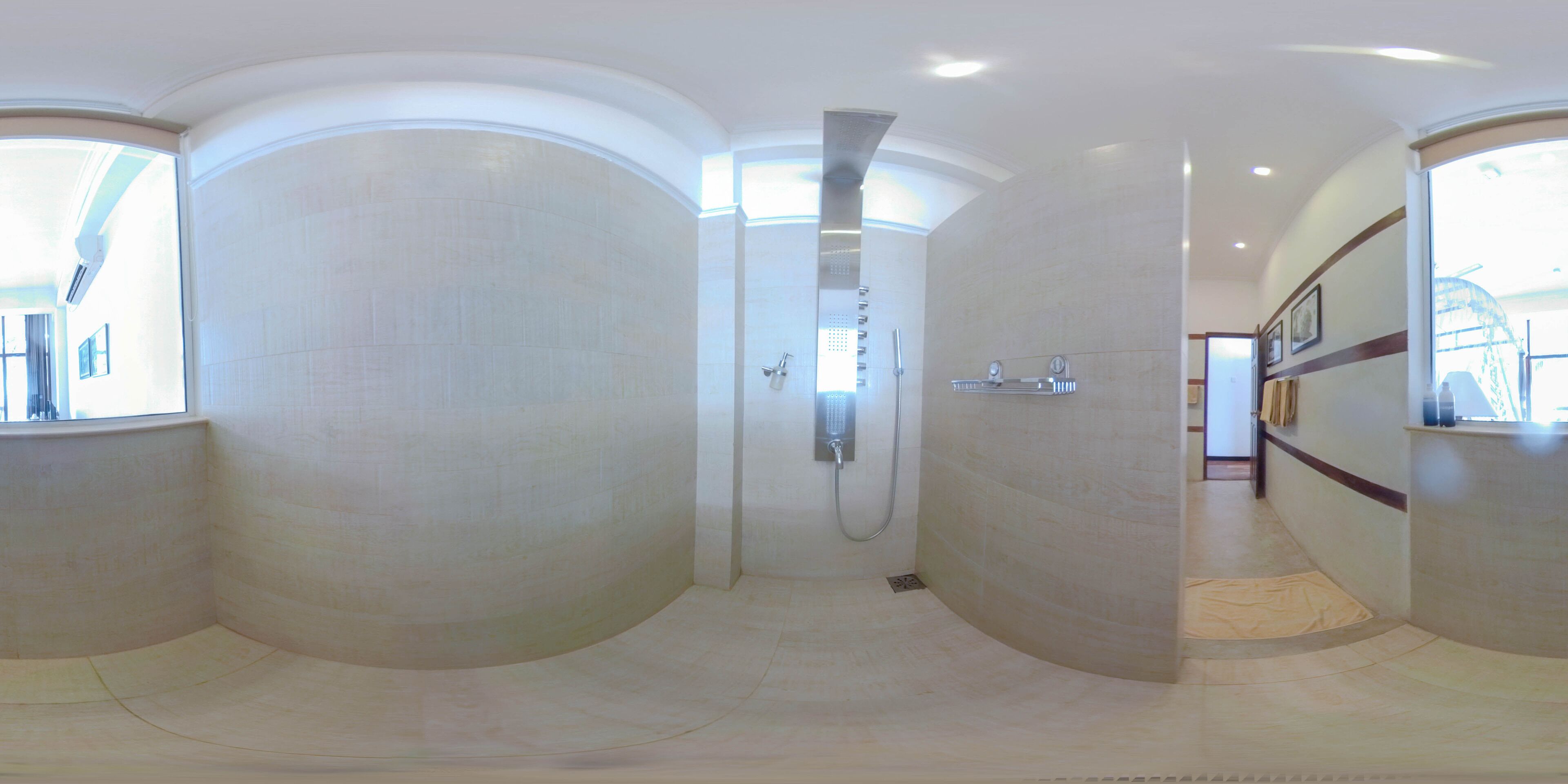 Un espace douche spacieux et aux lignes courbes, doté d’un design moderne, d’une pomme de douche visible et d’un sol carrelé.