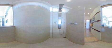 A spacious, curved shower area with a modern design, a visible showerhead, and a tiled floor.