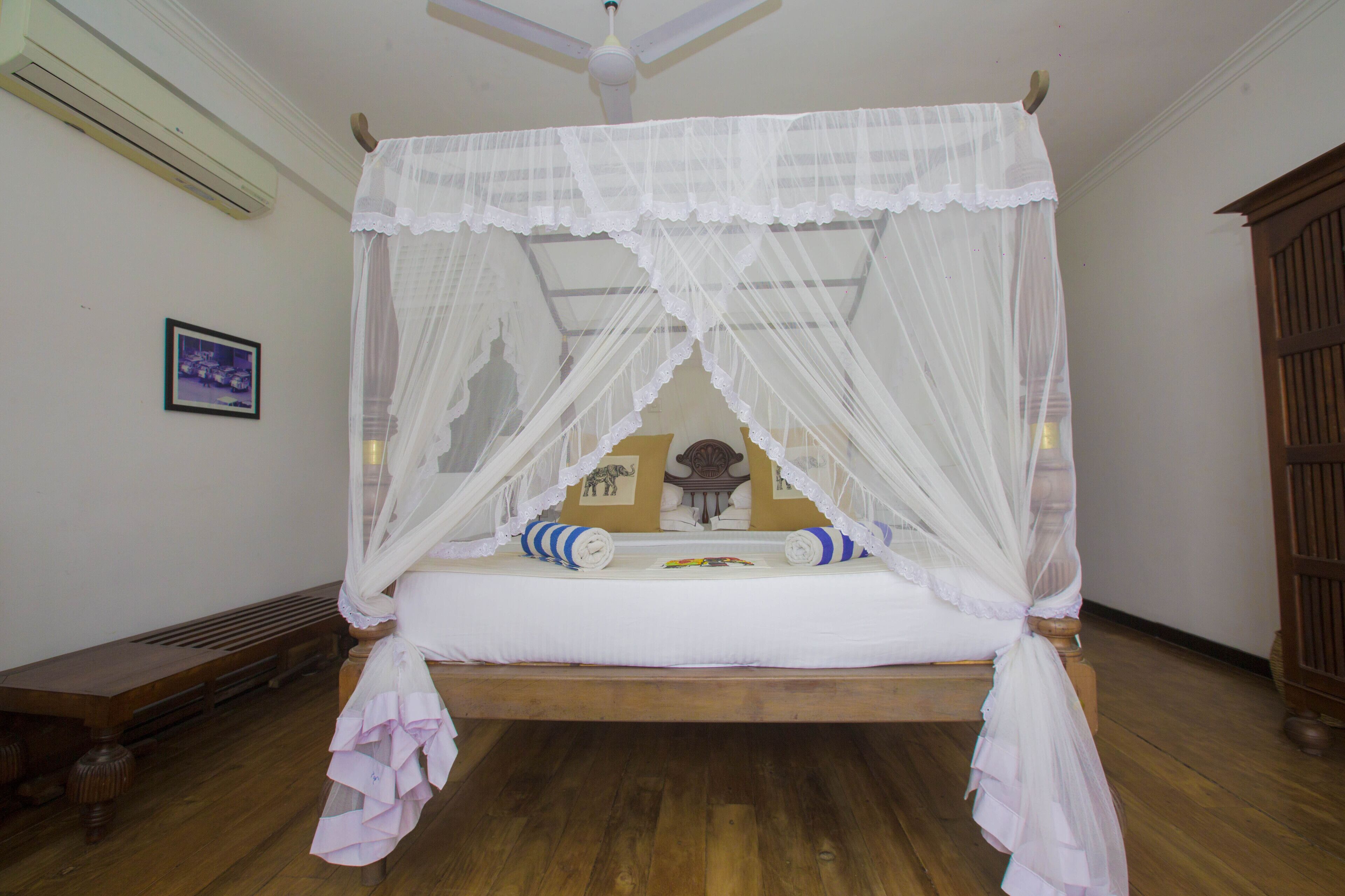 A four-poster canopy bed with a wooden frame and white bedding.