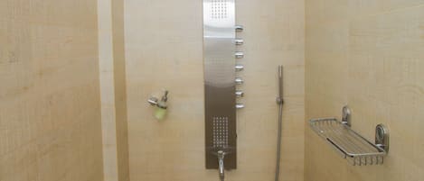 Une douche équipée d’un pommeau de douche à pluie vertical, d’un pommeau de douche à main et d’un porte-serviettes mural.