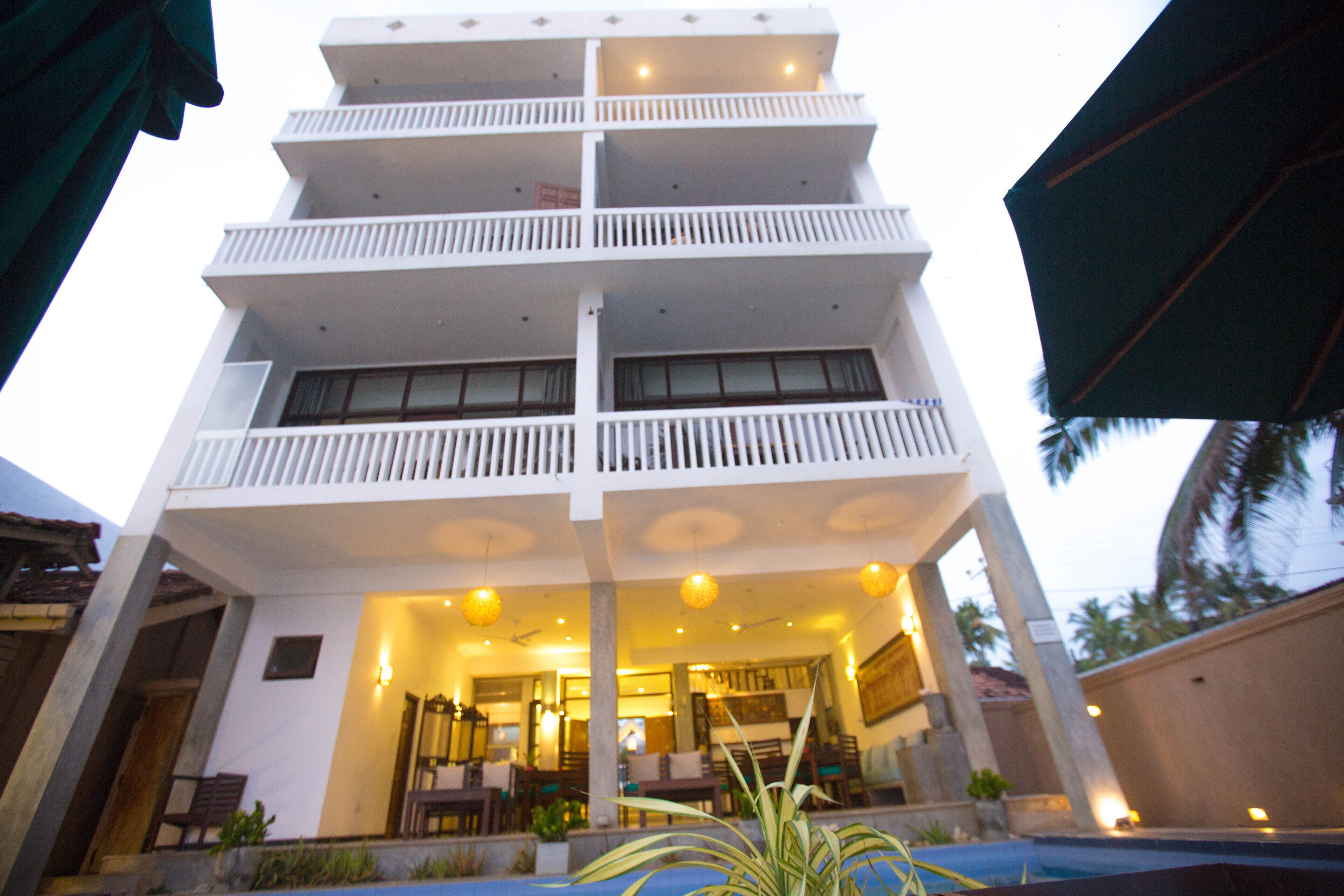 A multi-story hotel with balconies, a swimming pool, and a well-lit interior.