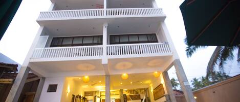 Un hotel de varios pisos con balcones, piscina y un interior bien iluminado.