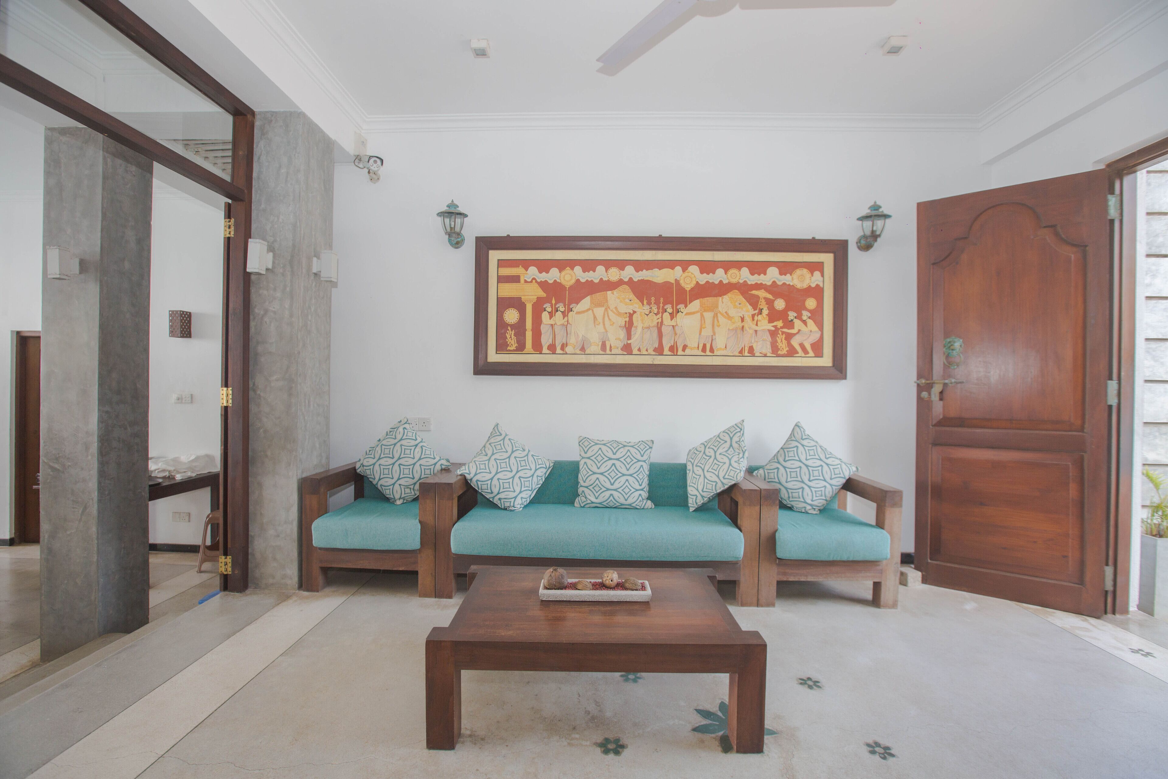 A living room with a wooden sofa, a coffee table, and a large painting on the wall.