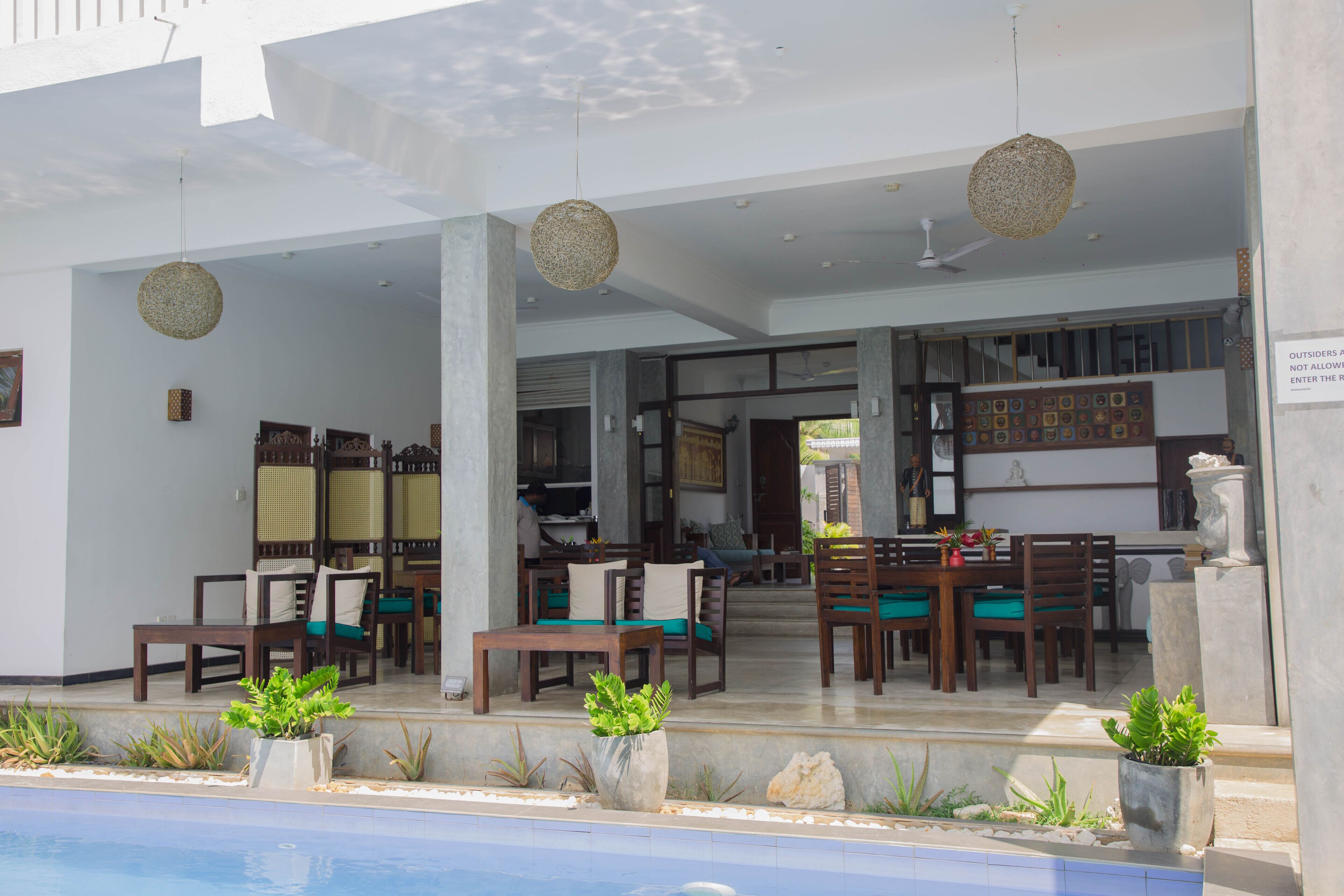 A poolside area with outdoor seating, a pool, and a covered entrance.