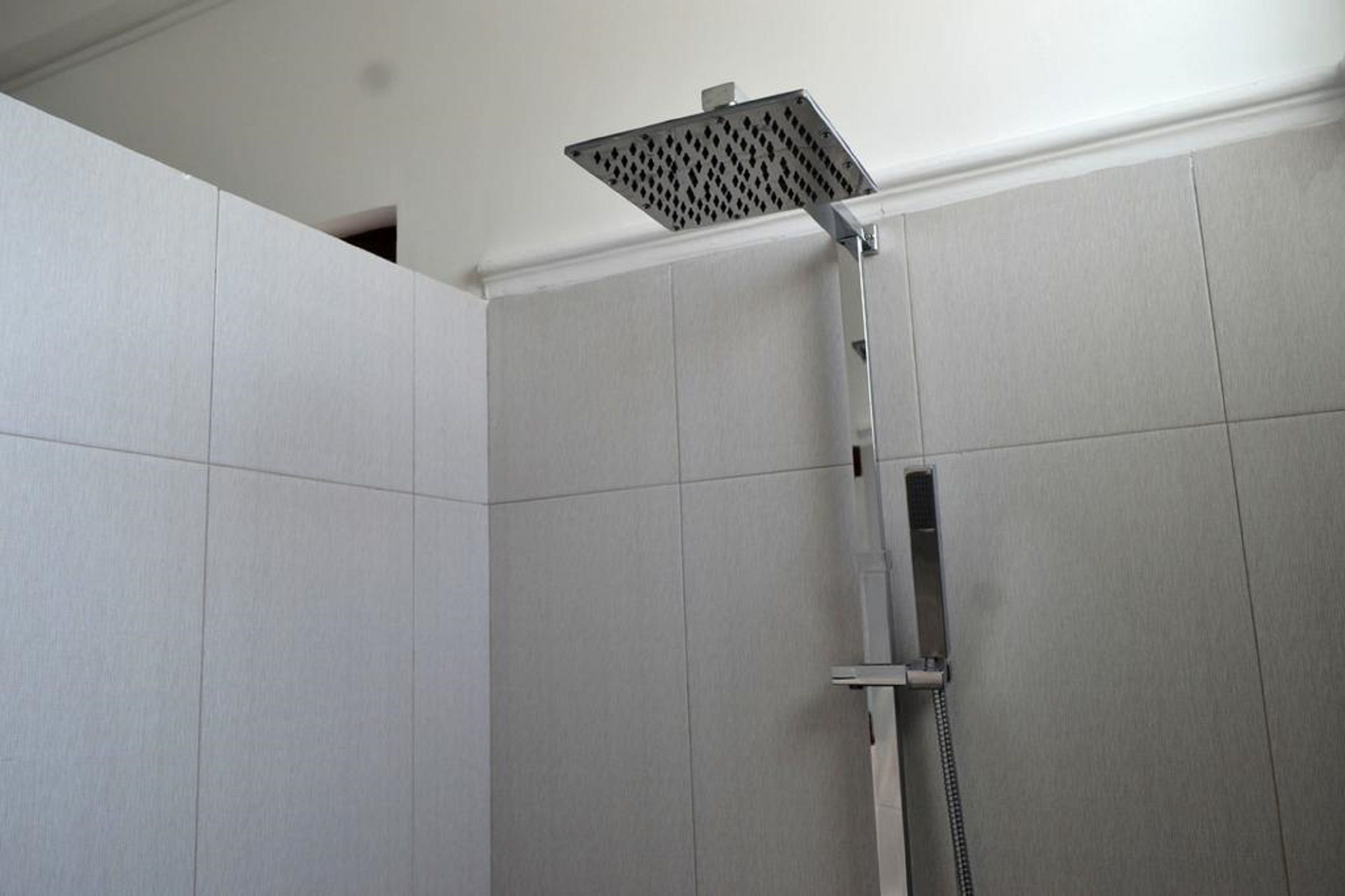 A shower with a square head and a handheld showerhead.